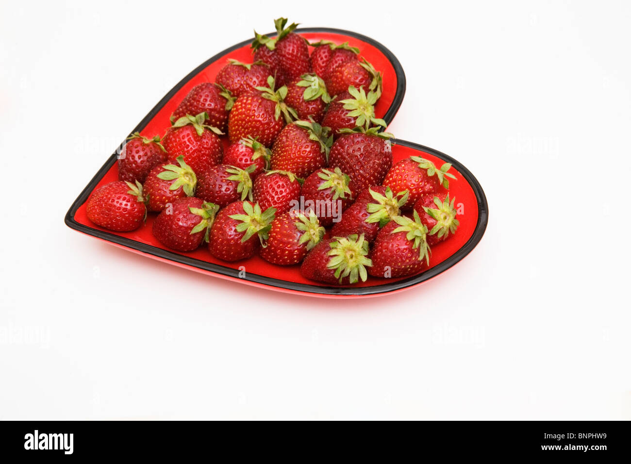A heart shaped plate of fresh strawberries Stock Photo
