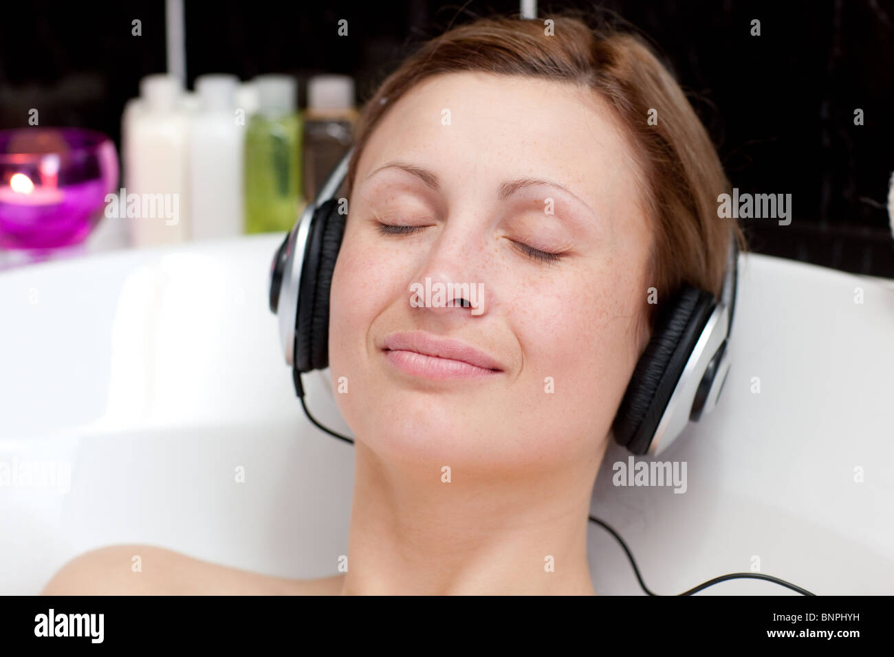 Closeup of a relaxed young woman listening music in a bubble bath