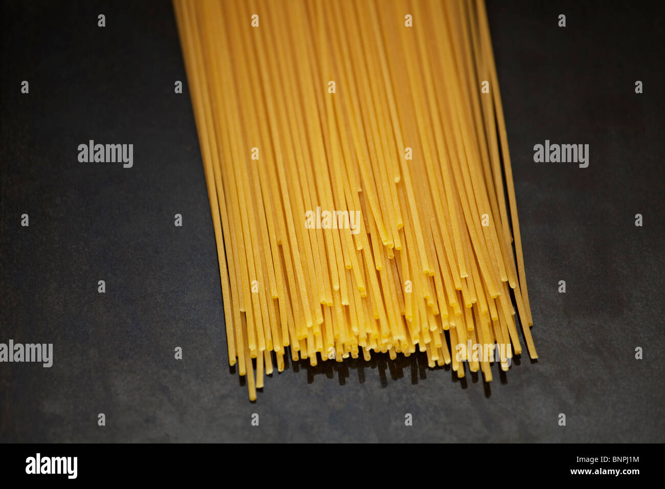 Dried spaghetti pasta on a black marble surface Stock Photo