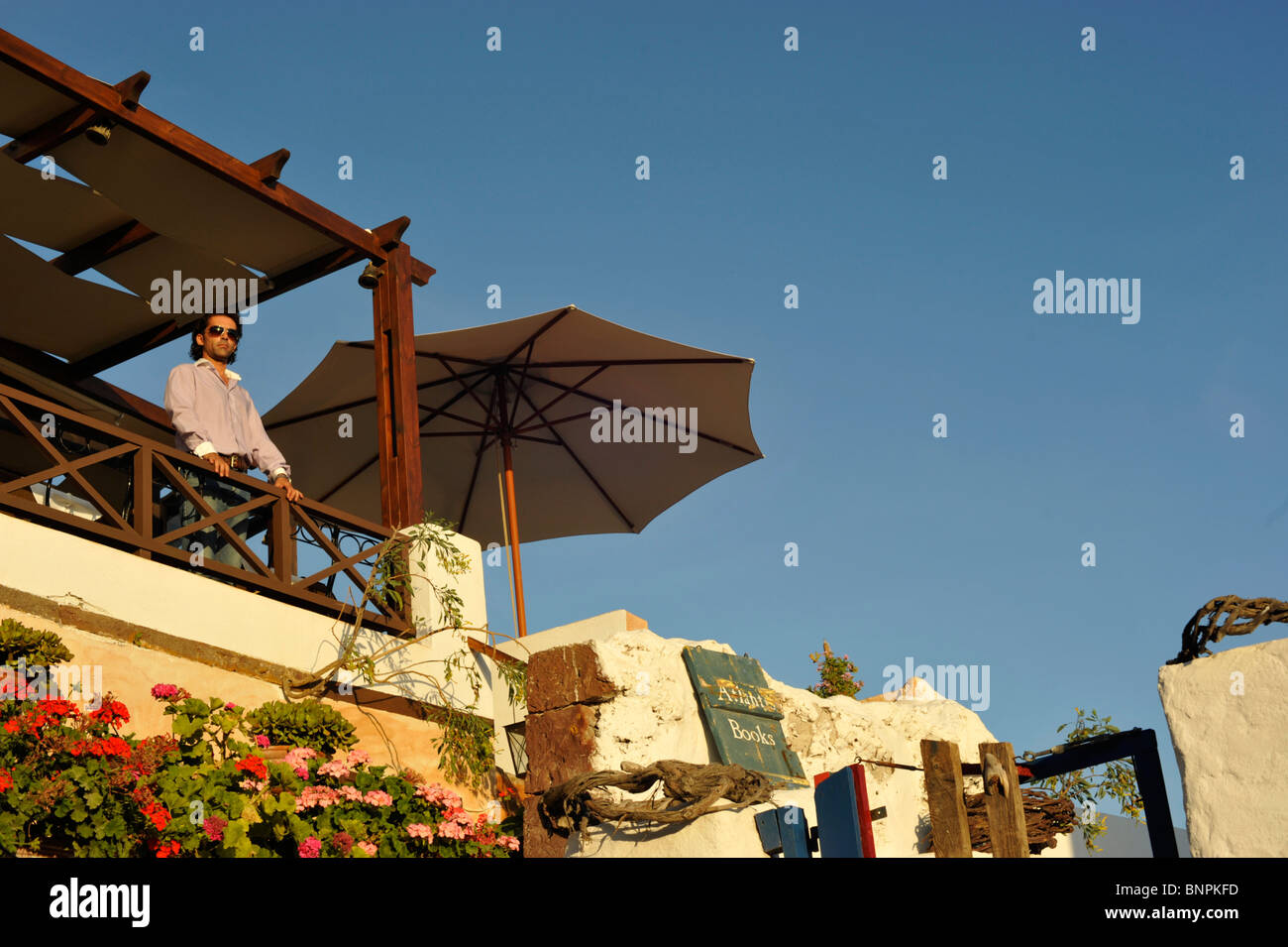 Waiter watching the sun set from an outdoor restaurant in the town of Oia Santorini Cyclades Islands Greece Stock Photo