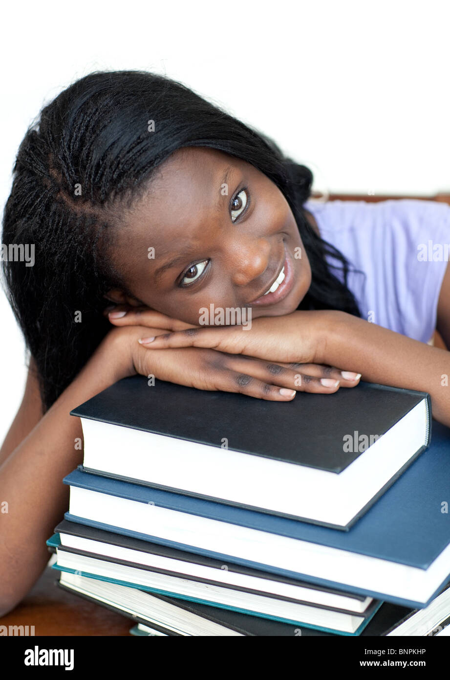 Smiling student leaning on a stack of books Stock Photo - Alamy