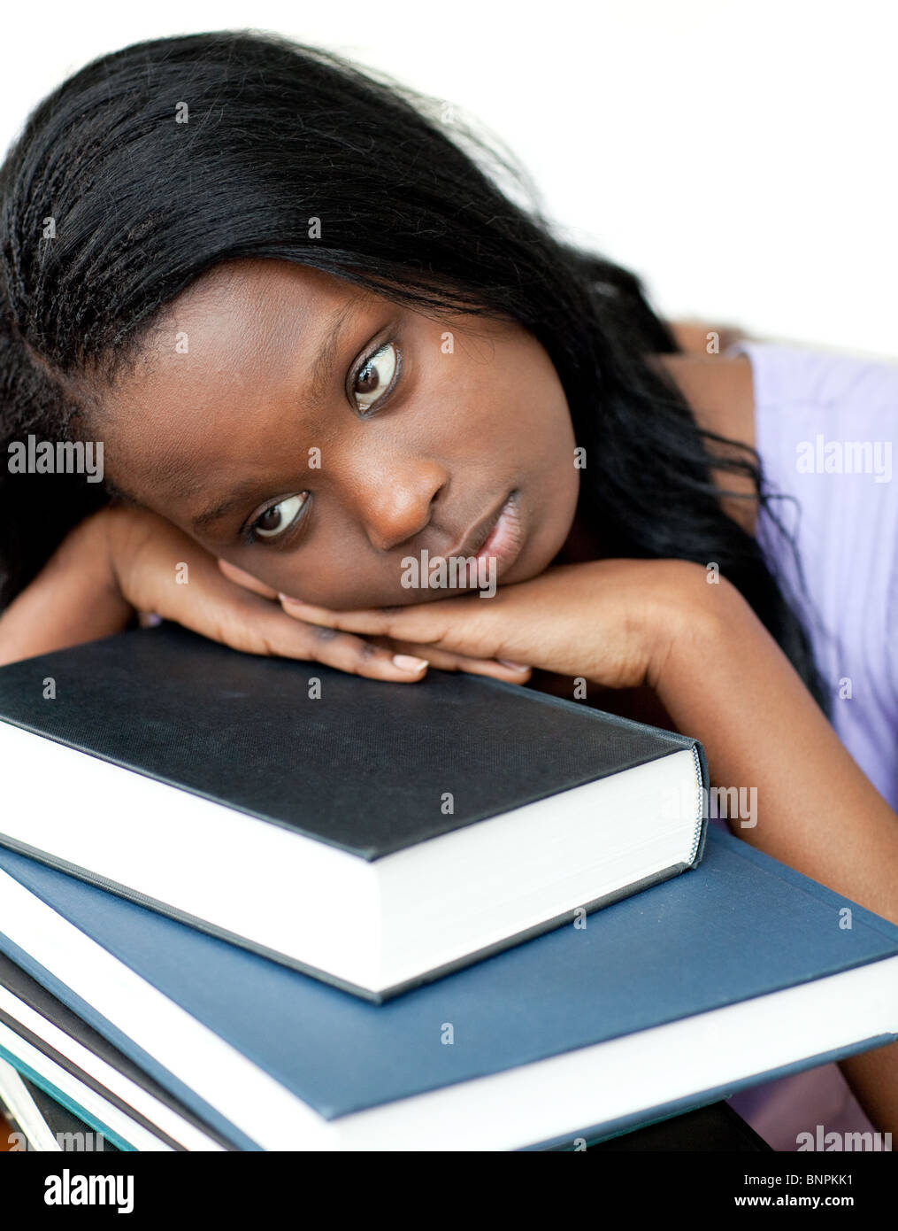 Annoyed student leaning on a stack of books Stock Photo - Alamy