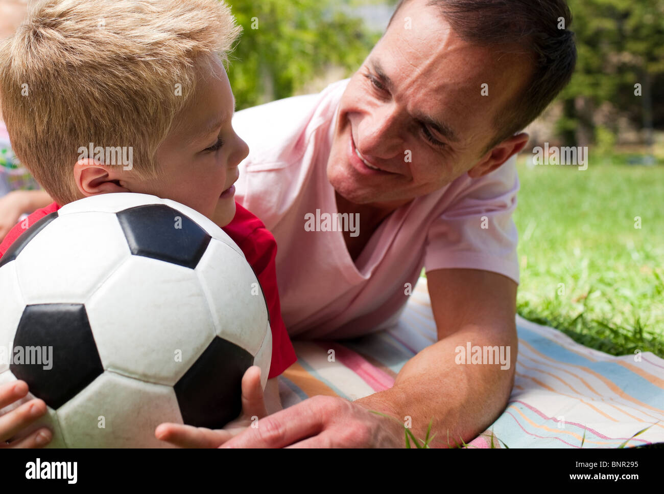 Close Up Of An Attentive Father And His Son Holding A Soccer Ball Stock