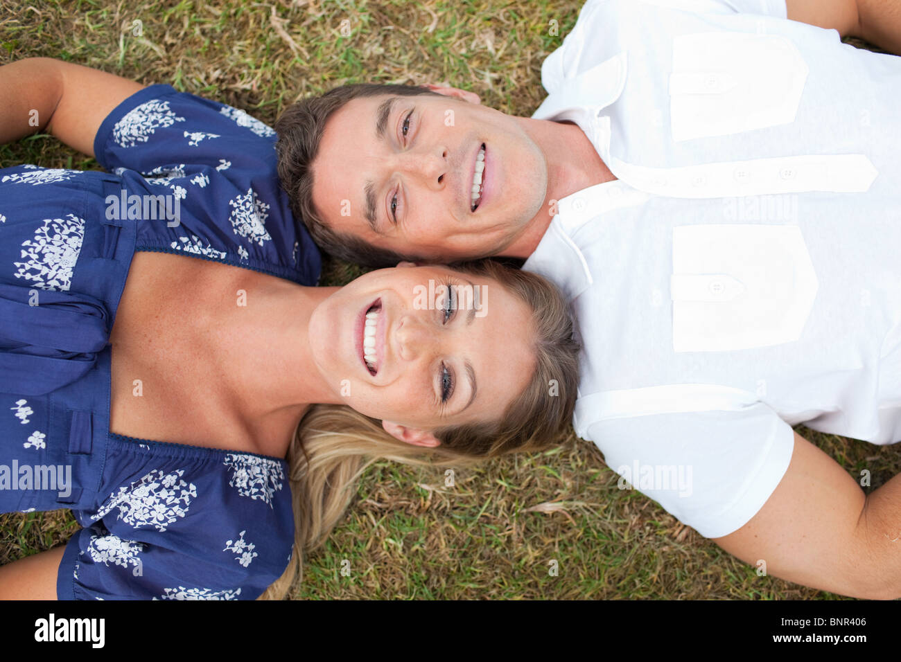 Happy couple lying on the grass Stock Photo - Alamy