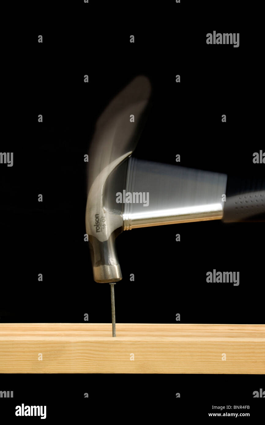 An 'action' shot of a claw hammer hitting a nail on the head Stock