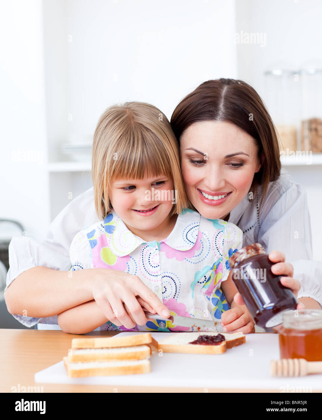 Smiling mother helping her daughter prepare the breakfast Stock Photo