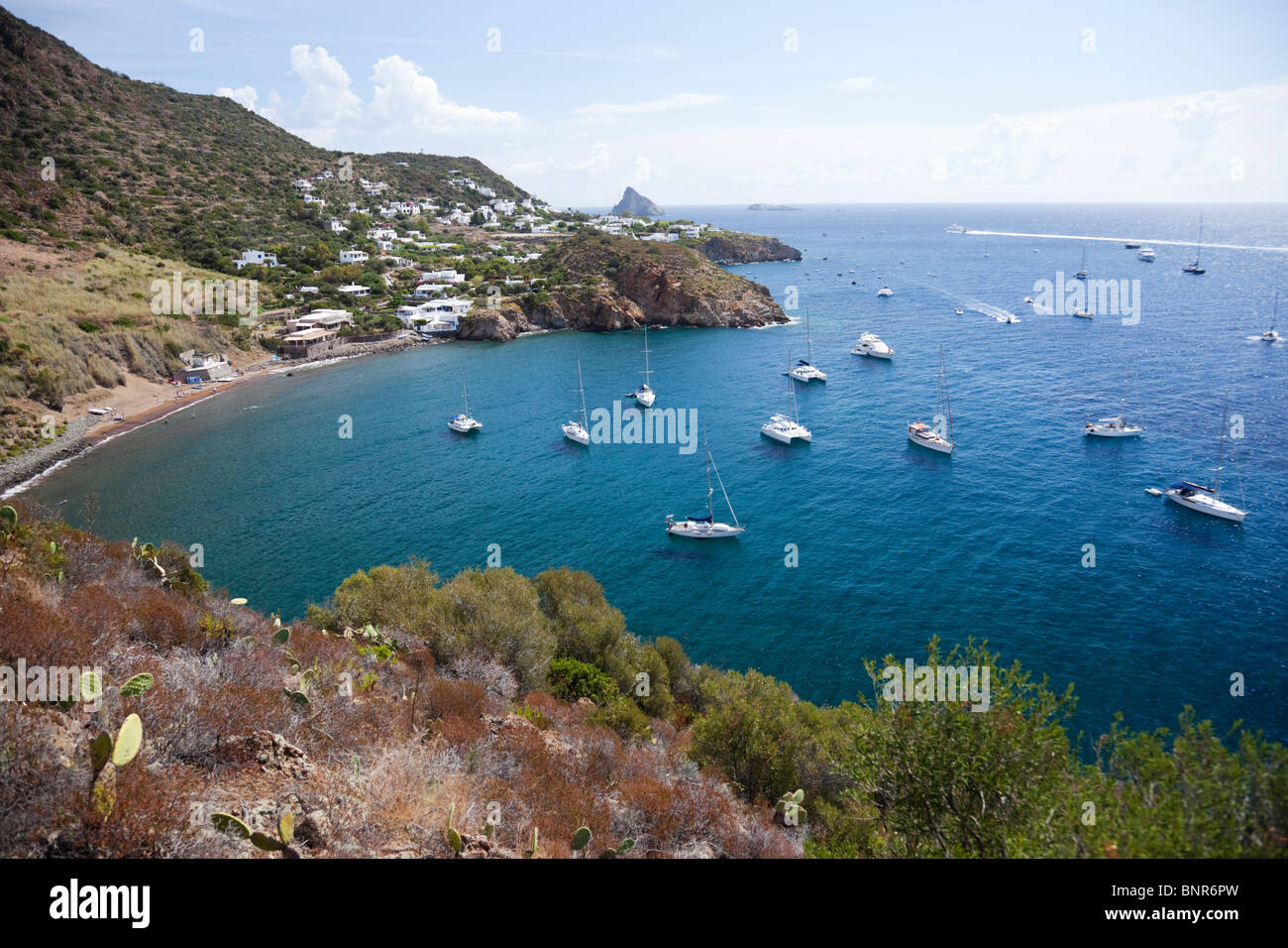 Overlooking sailboats in bay named Caletta degli Zimmari in island Panarea of Aeolian Islands. Stock Photo