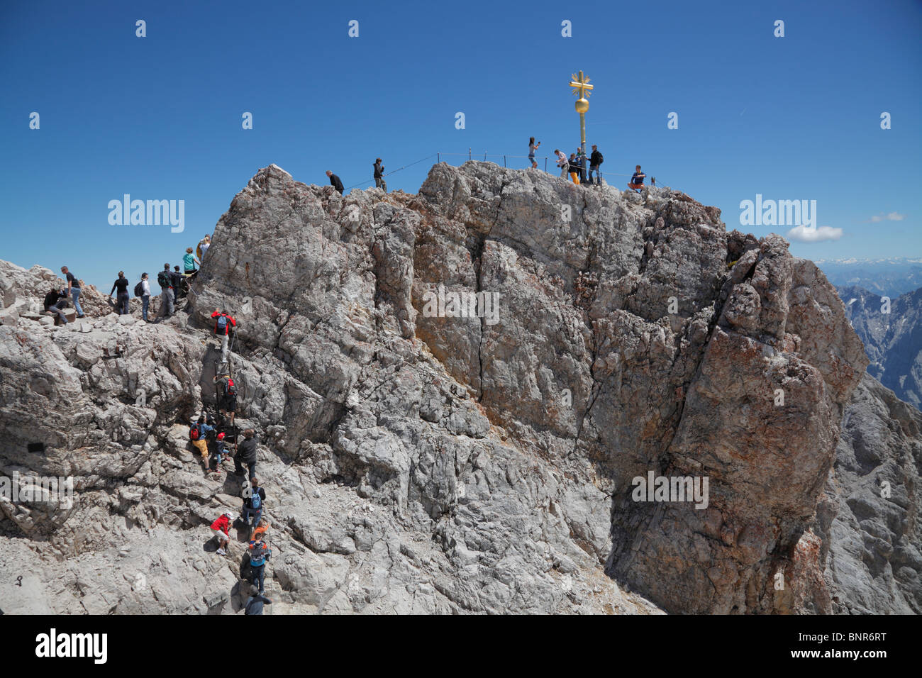 Tourists climbing to the Golden Cross - the highest point in Germany on the summit of Zugspitze at 2,962m above sea level - on a sunny summer day Stock Photo