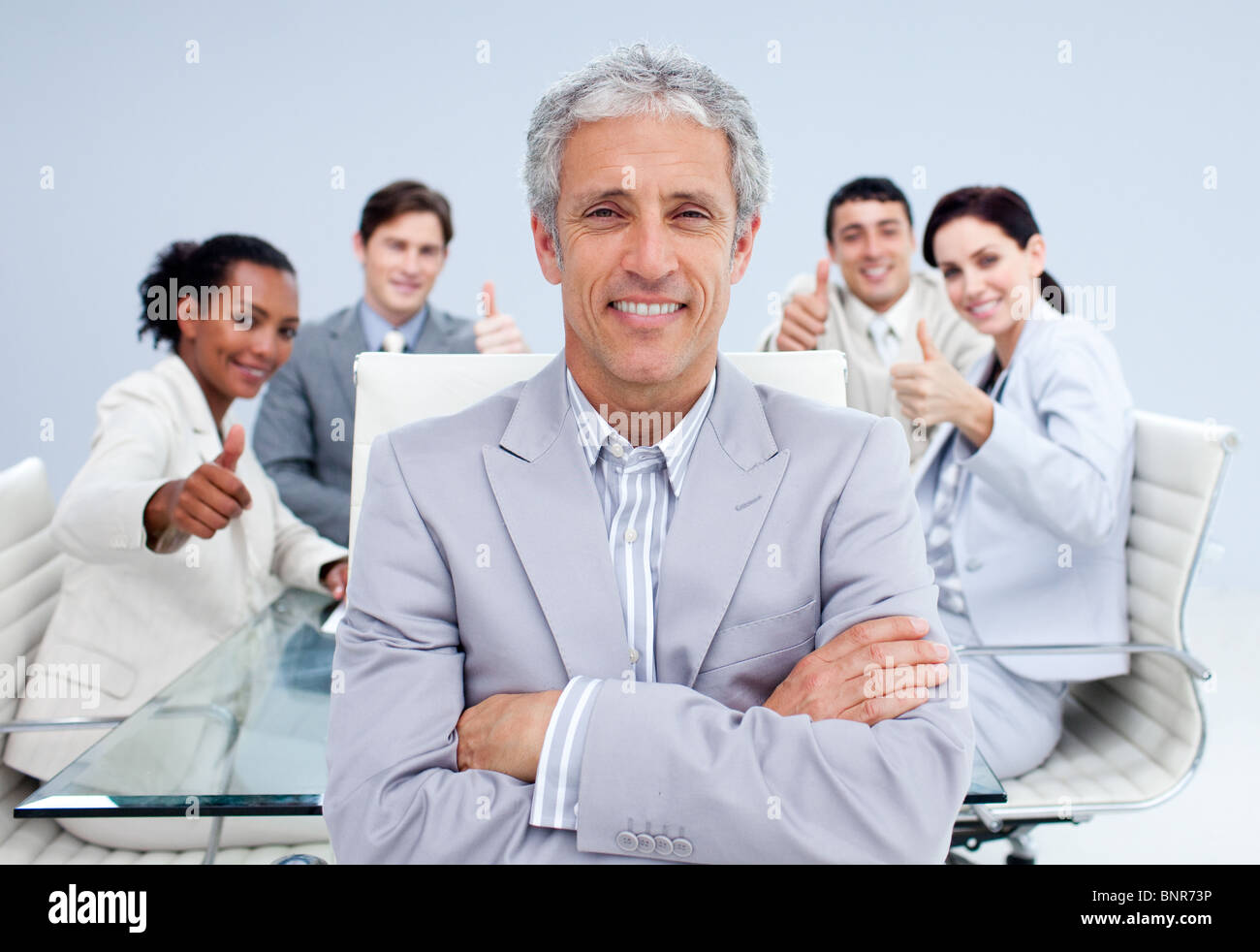 Happy businessman leading his happy team with thumbs up Stock Photo - Alamy