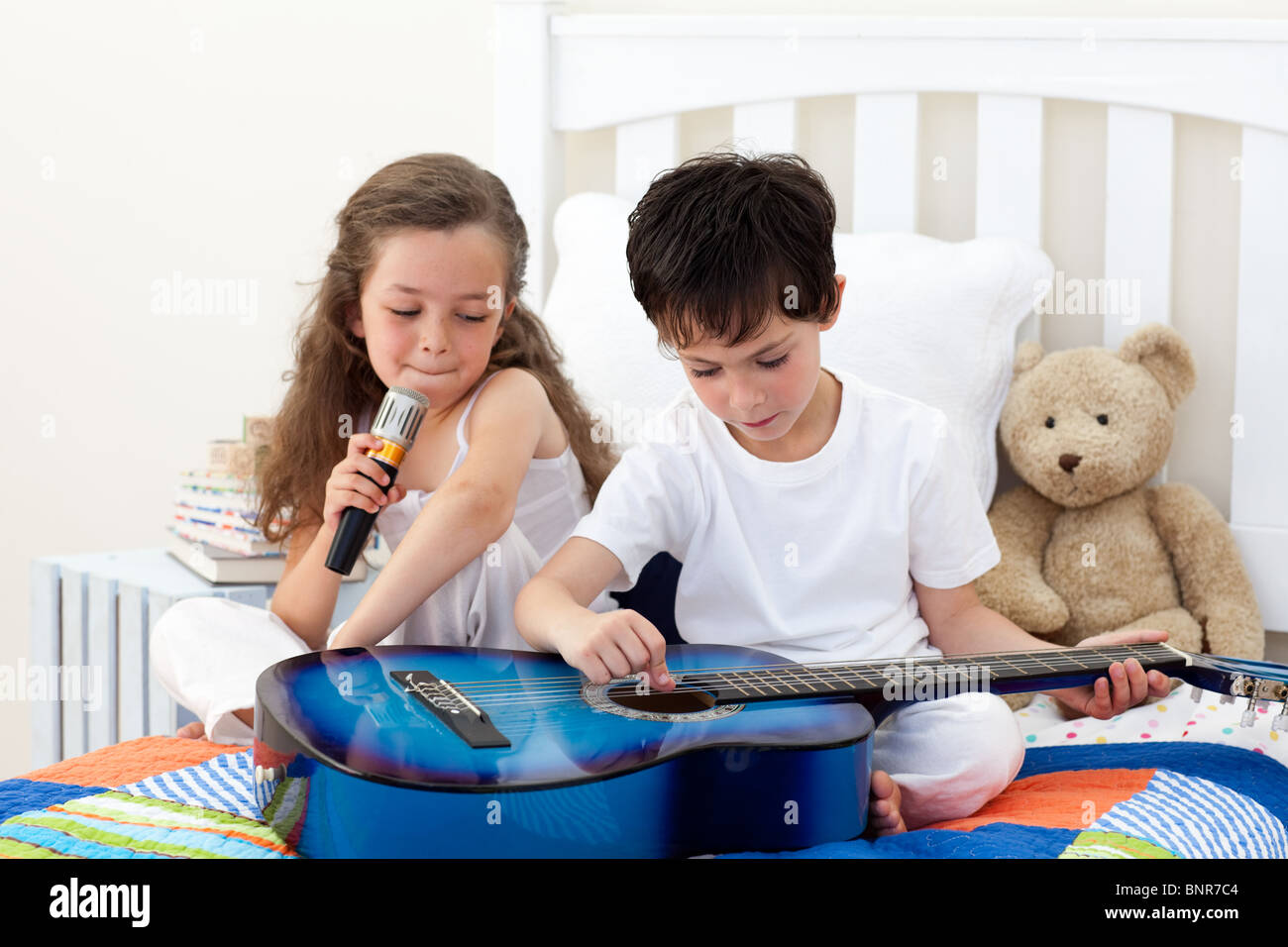 Siblings singing and playing guitar Stock Photo