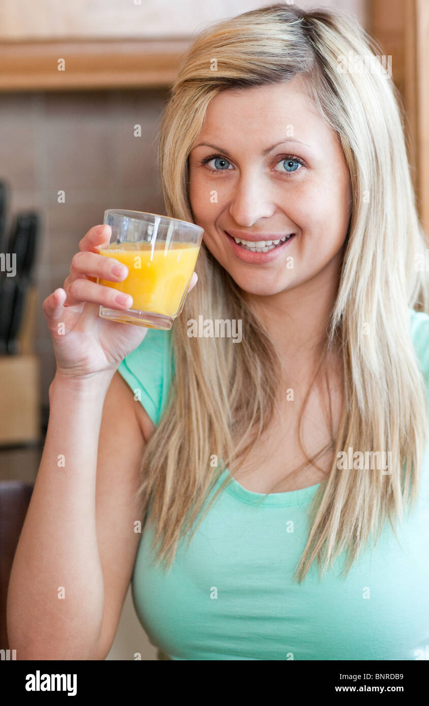 Enthusiastic woman drinking orange juice in a kitchen Stock Photo Alamy