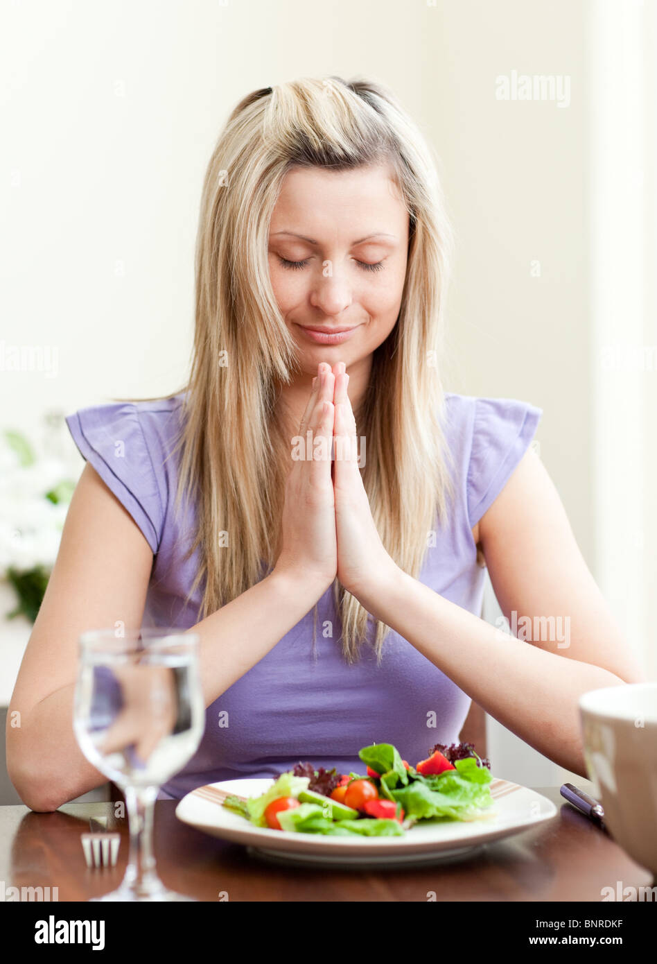 Young woman saying grace before dinner Stock Photo Alamy