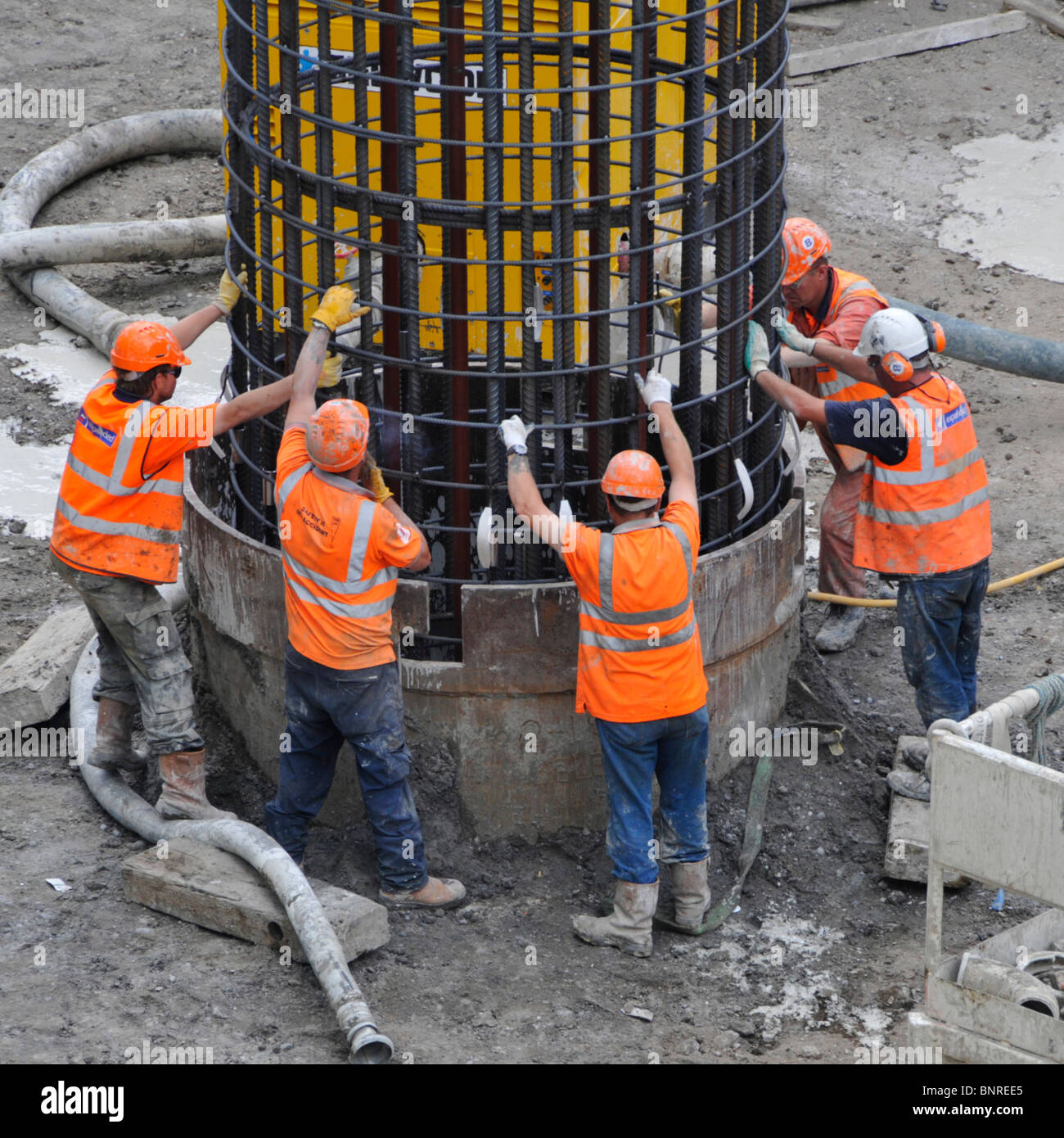 Steel reinforcing cage being lowered by crane into pile casing for foundations on Crossrail construction site Stock Photo