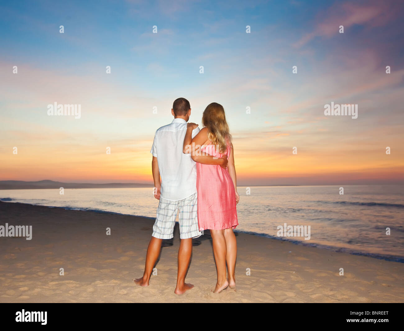 Couple on the beach at sunrise time Stock Photo - Alamy