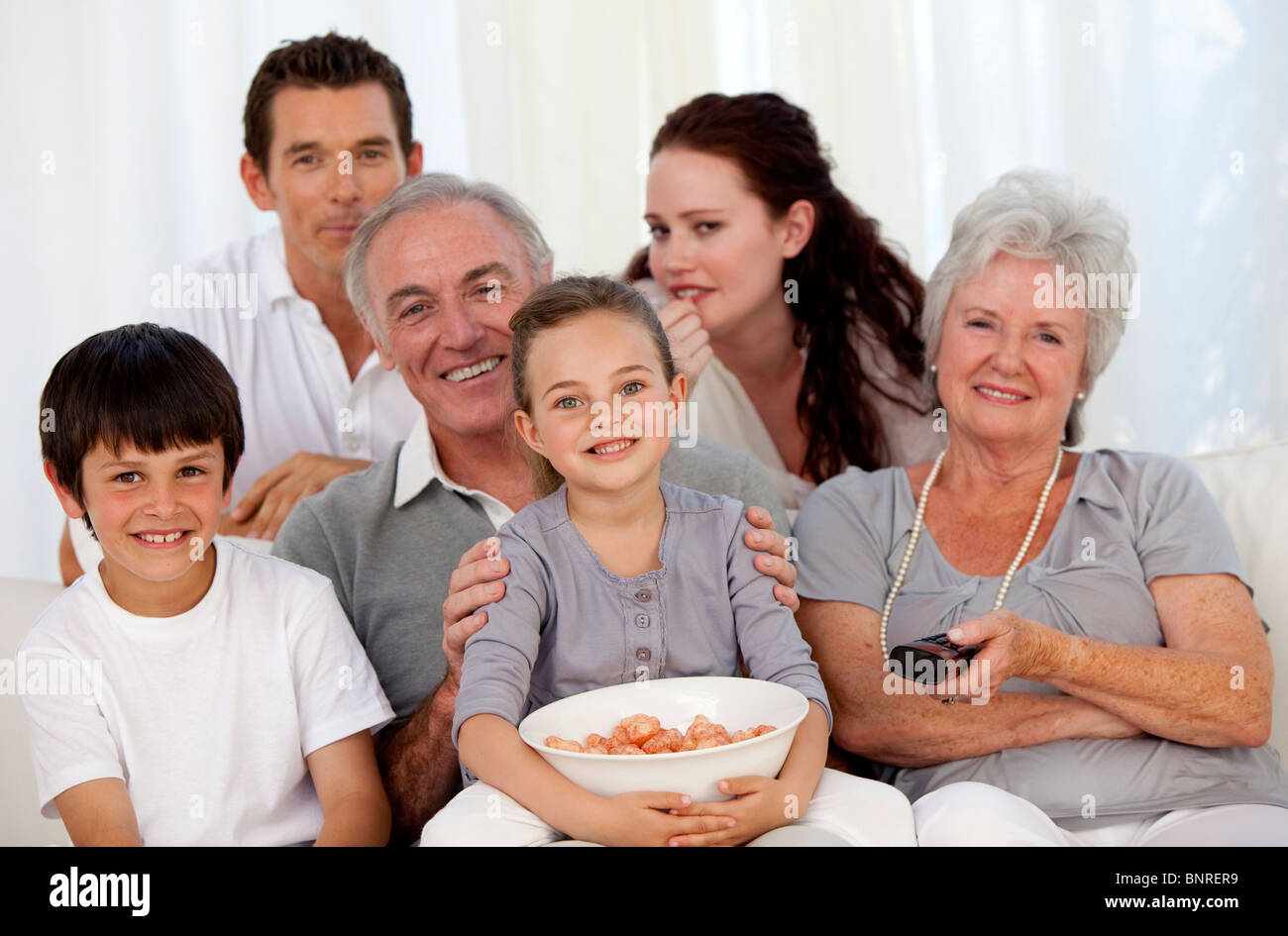 Family eating chips and watching television Stock Photo - Alamy