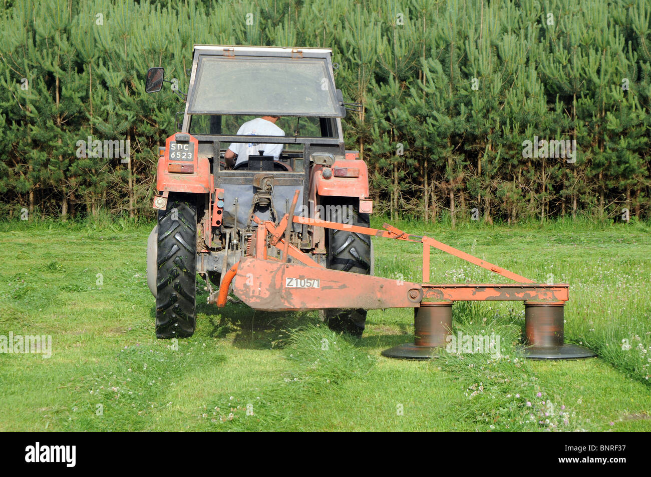 haymaking on countryside, Poland. Polish ursus 3512 tractor with rotary mowers (also called drum mowers) Stock Photo