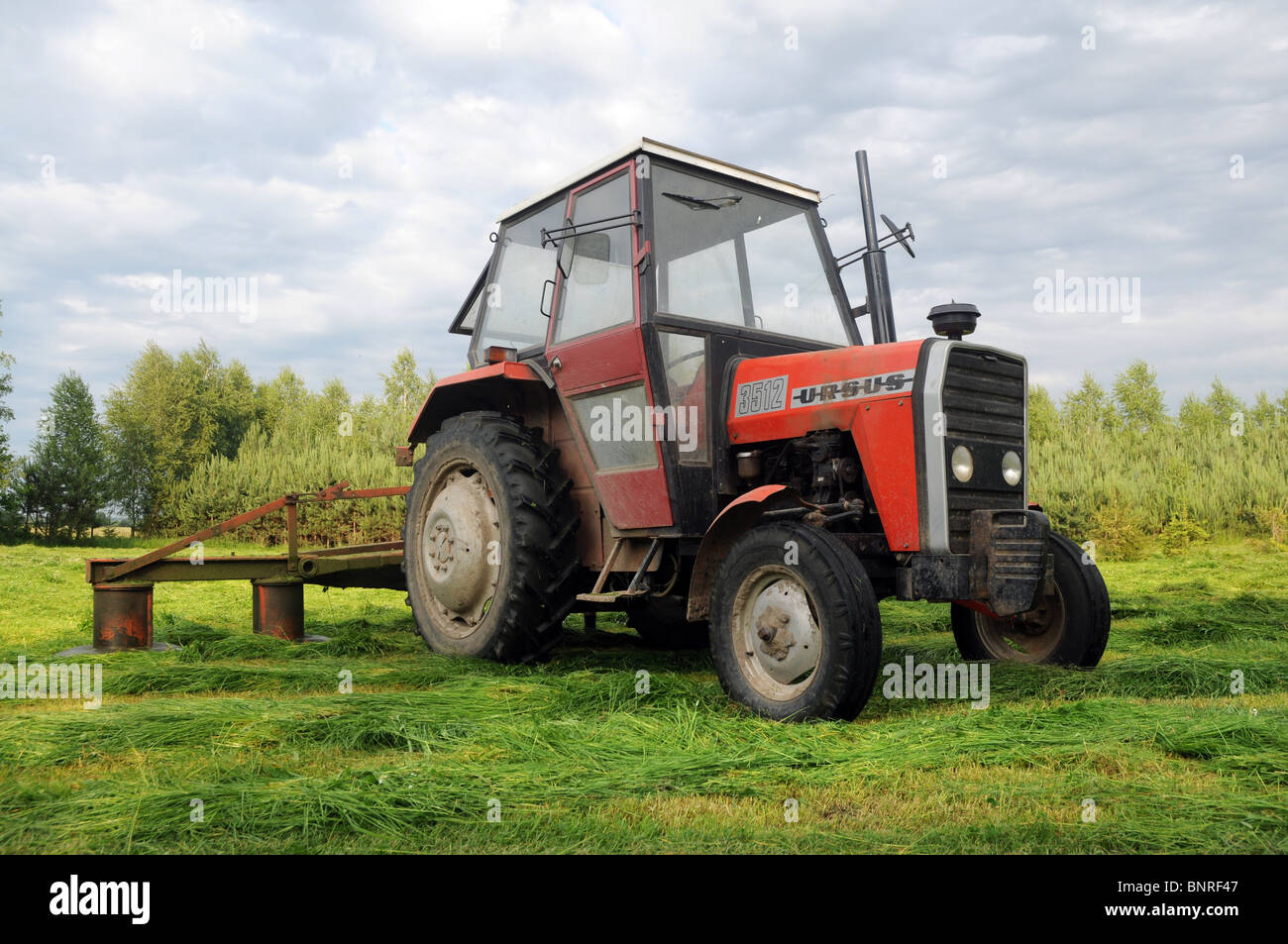 haymaking on countryside, Poland. Polish ursus 3512 tractor with rotary mowers (also called drum mowers) Stock Photo
