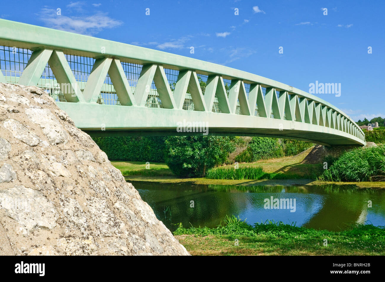 Modern metal single span arch bridge over river - Preuilly-sur-Claise, France. Stock Photo