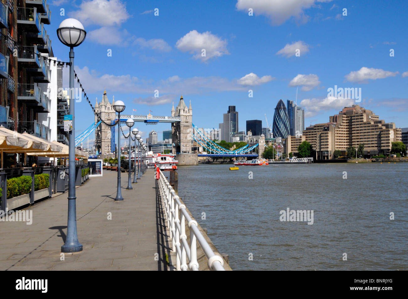 Pedestrian walkway with Street Lamps beside River Thames landscape view of Tower Bridge & City of London Skyline from Butlers Wharf Southwark Stock Photo