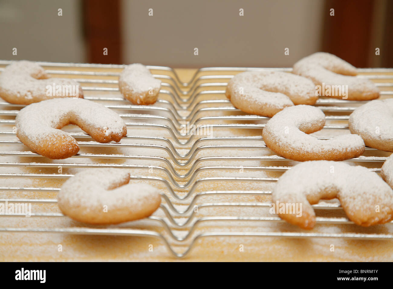 crescent cookies cooling on a baking rack sprinkled with powered sugar Stock Photo