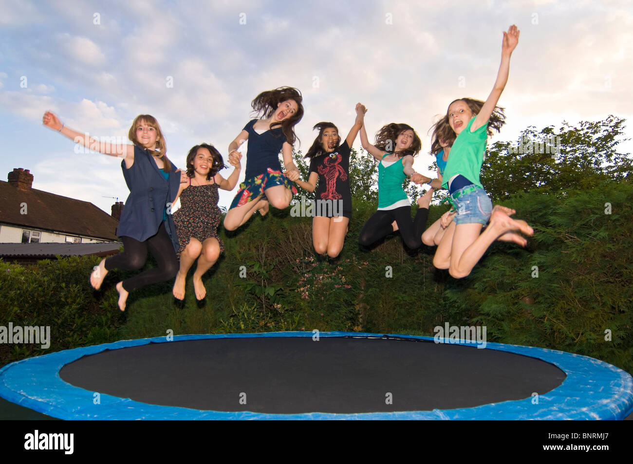 Horizontal close up portrait of a group of girl friends jumping on a  trampoline in a garden Stock Photo - Alamy