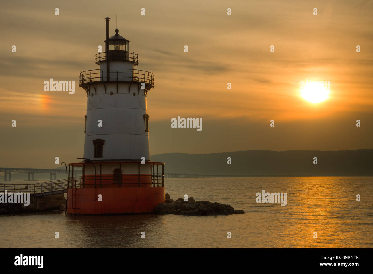 The Tarrytown Lighthouse on the Hudson River under a hazy sky and parhelion near sunset. Stock Photo