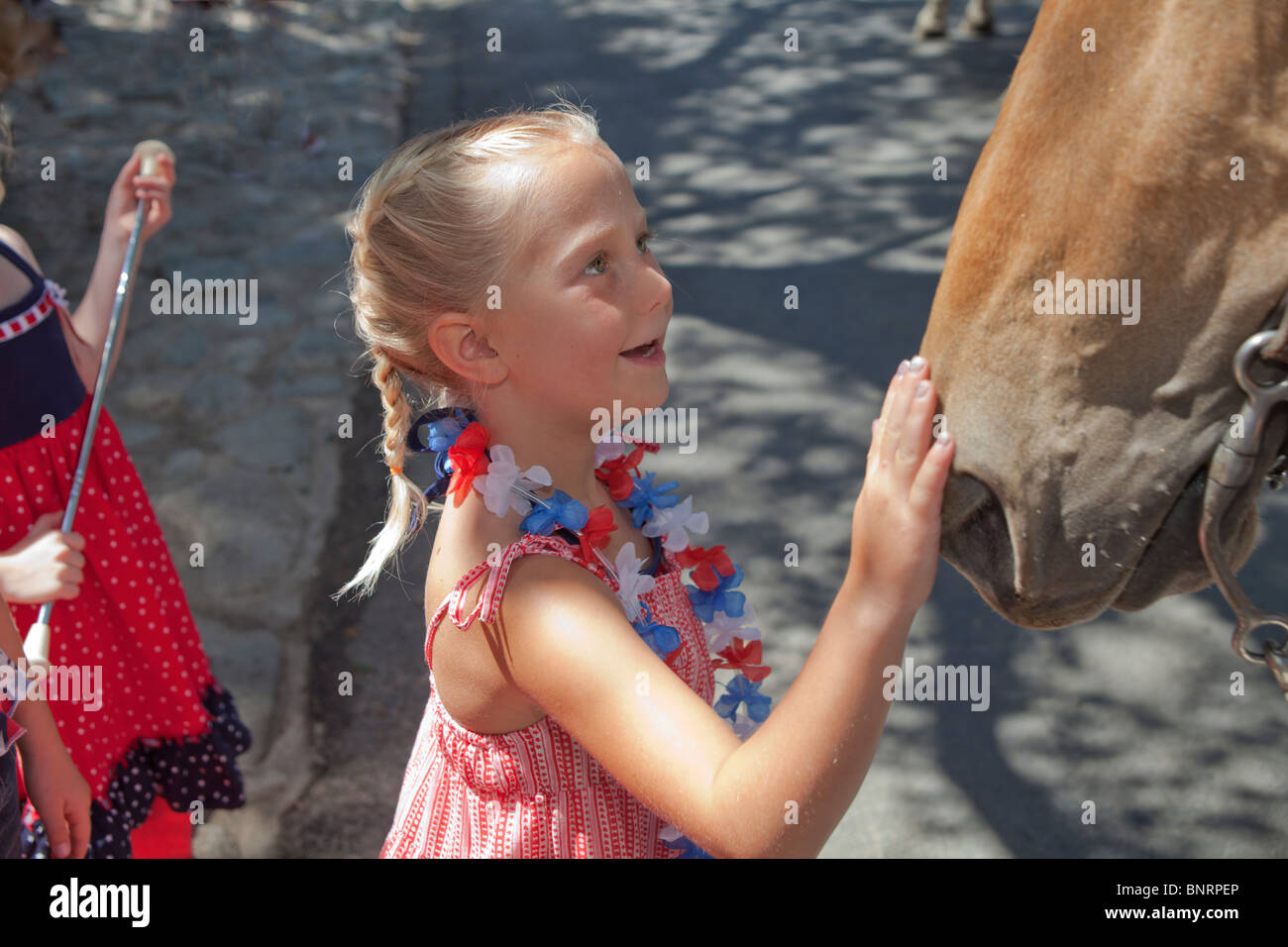 Wide-eyed smiling smile smiles 5-6 year old petting loving loves awed fascination fascinated expressive horses Independence Day United States  MR Stock Photo