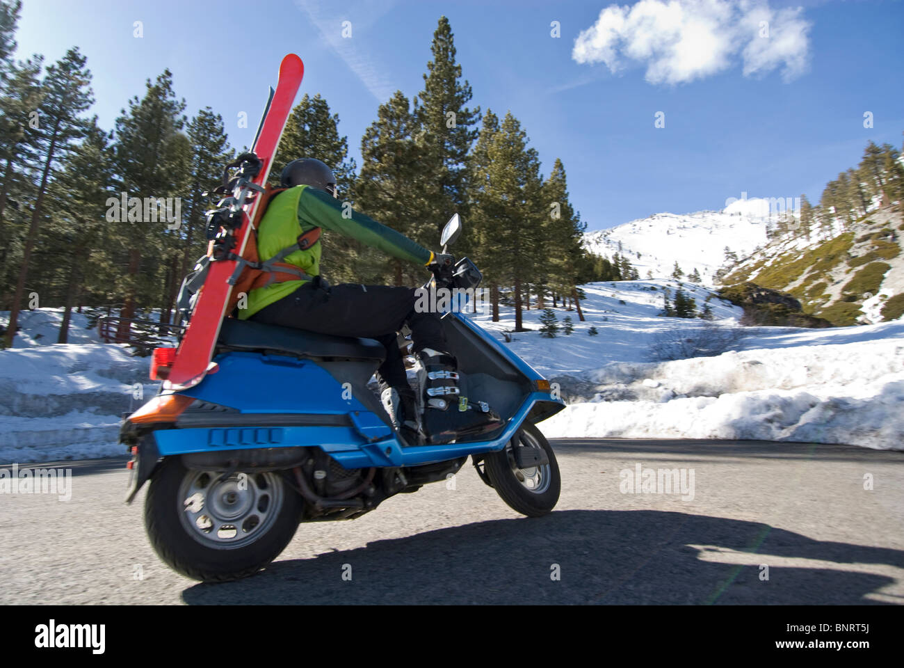 A young man rides a scooter to the start of the backcountry trail in