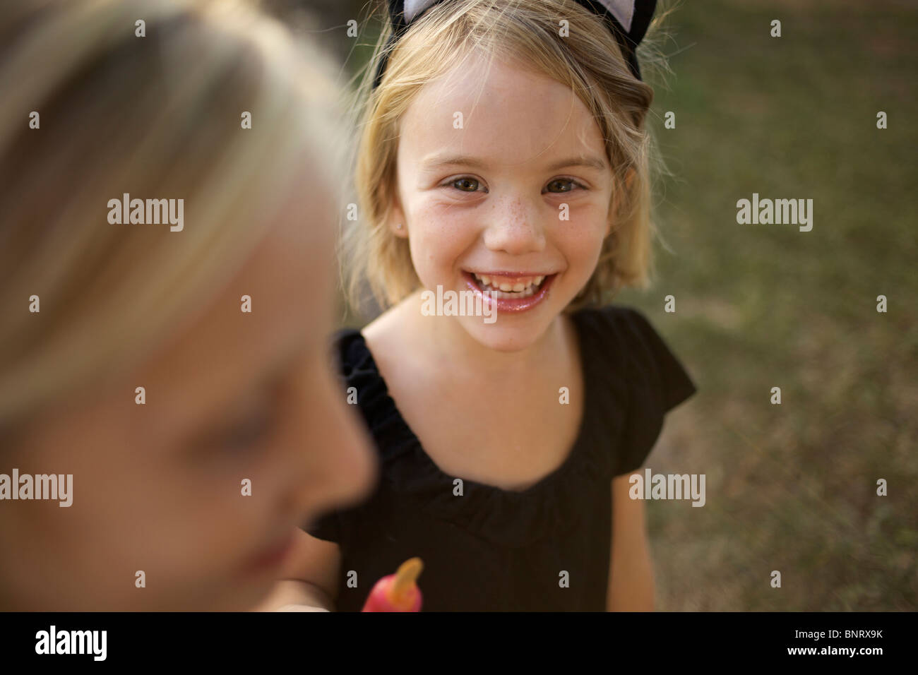 Girl holding her cold treat, wearing cat ears, looks at the camera and