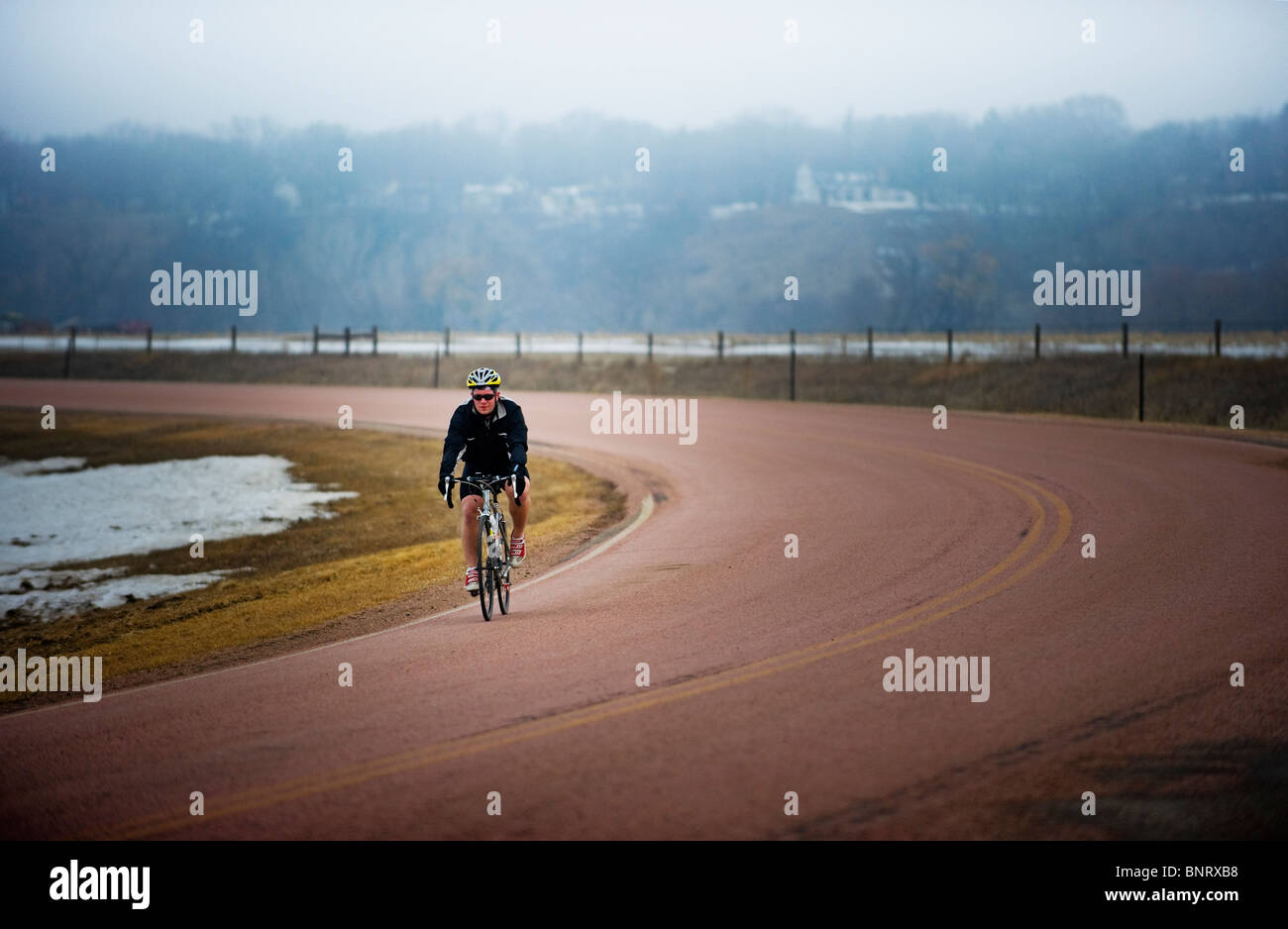 Man bicycles on a cold and foggy winter day. Stock Photo