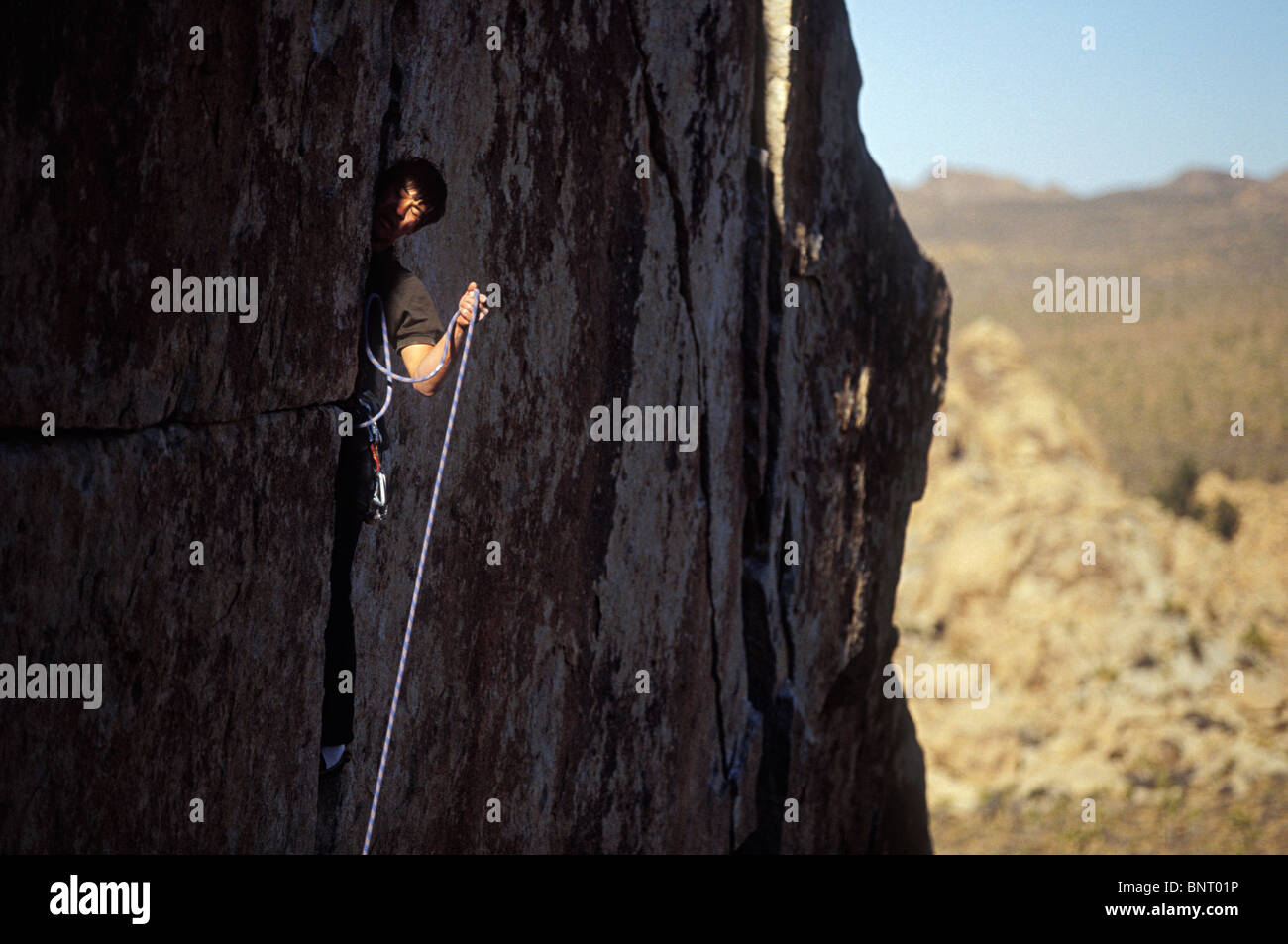 Man on cliff face struggles to pull up rope Stock Photo - Alamy