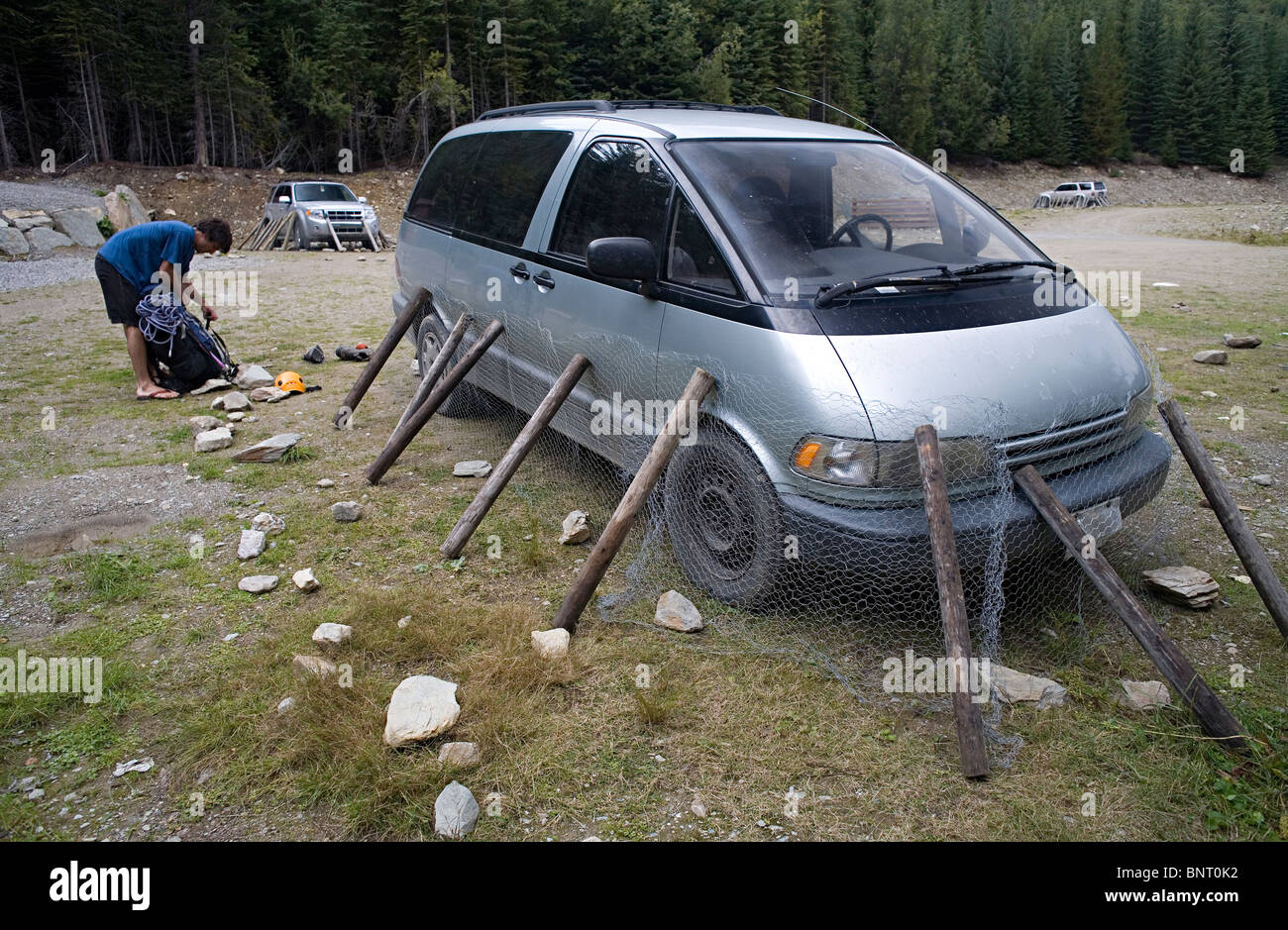 Man loads his backpack and his vehicle that is wrapped in chicken wire to protect from porcupines. Stock Photo