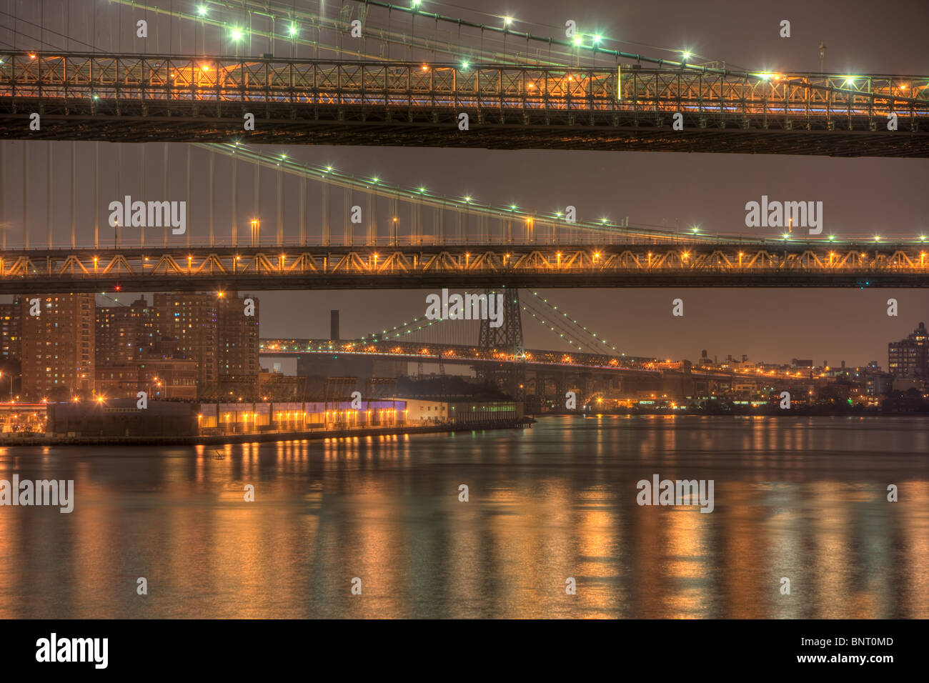 The Brooklyn, Manhattan, and Williamsburg bridges on the East River at night in New York City. Stock Photo