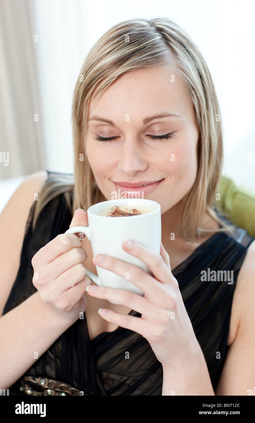Relaxed woman drinking a coffee sitting on a sofa Stock Photo - Alamy
