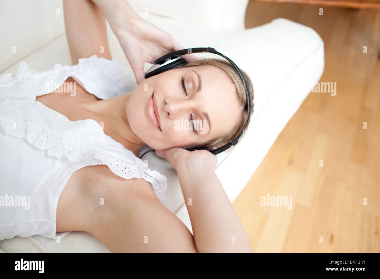Cute young woman listening music lying on a sofa Stock Photo - Alamy