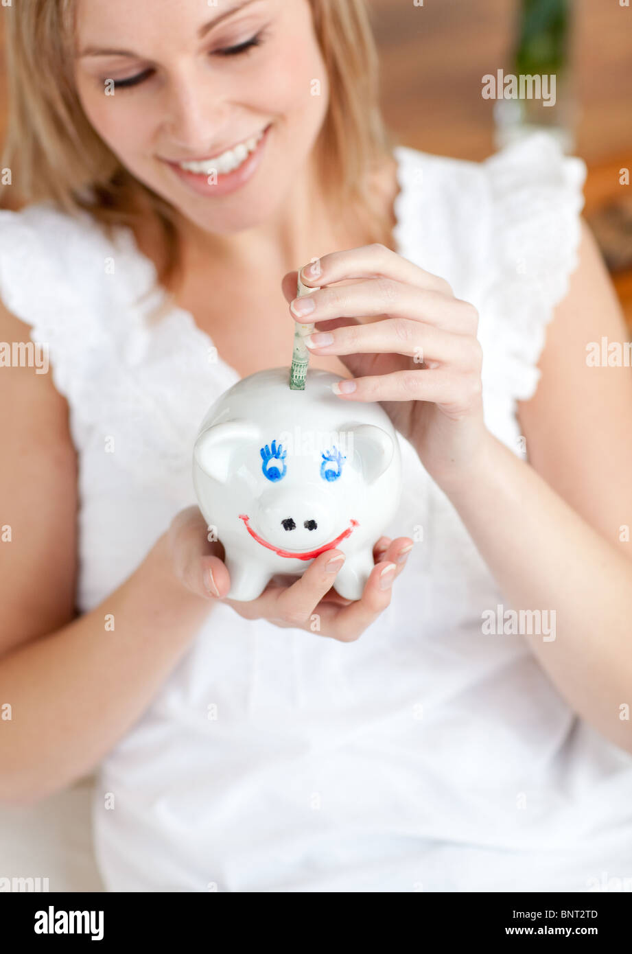 Attractive woman saving money in a piggy-bank Stock Photo - Alamy