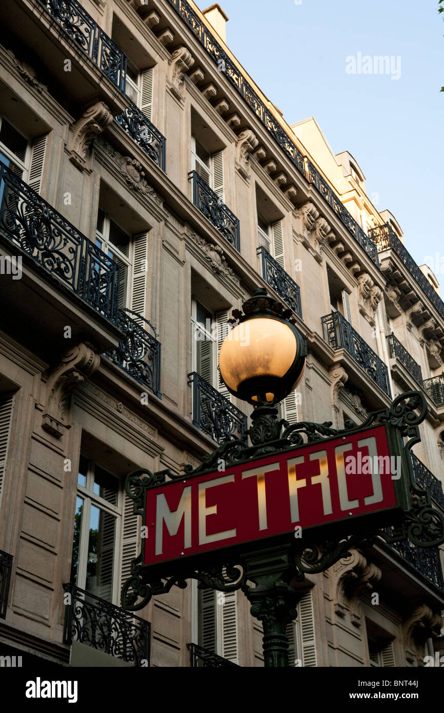 Paris Metro sign with ornate lamp above in a Paris street with typical Parisienne building in background Stock Photo