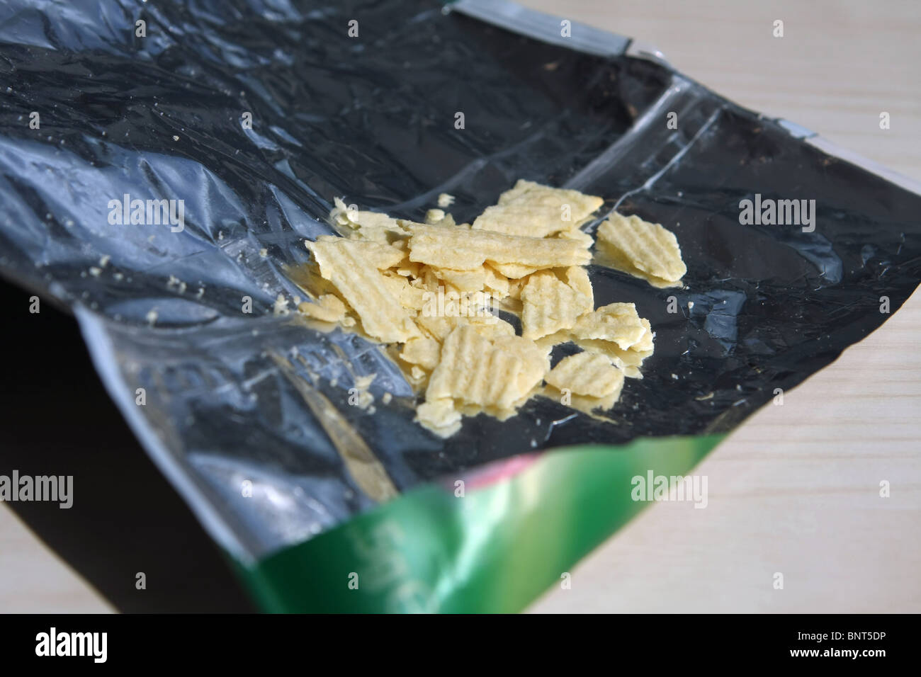 a few bits of crisps left in a torn open crisp bag Stock Photo