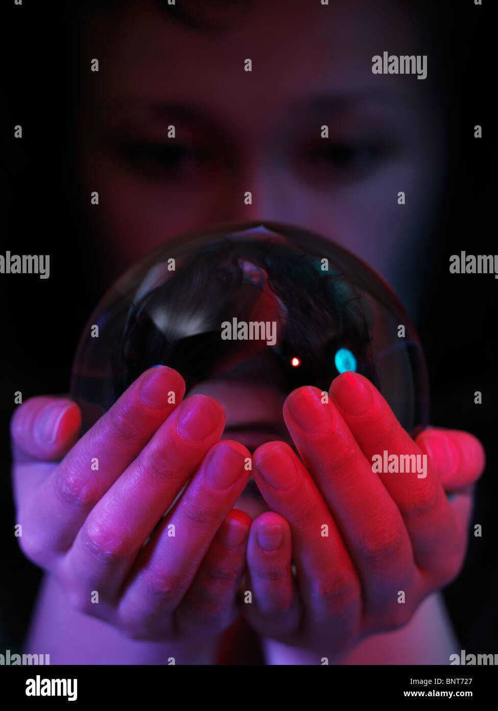 Woman looking into a crystal ball in her hands Stock Photo