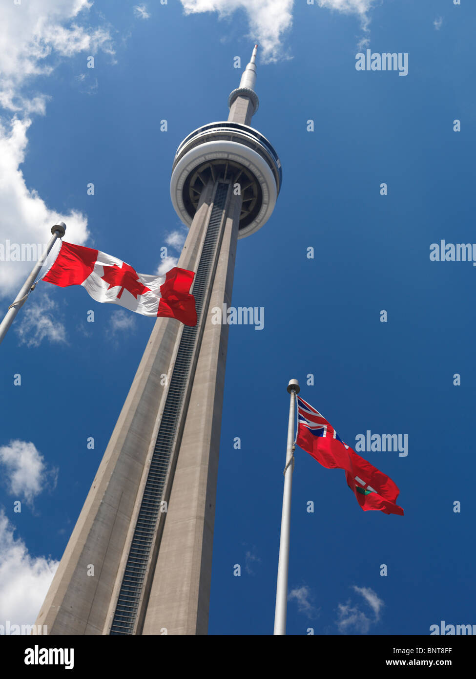 Ontario and Canada flags flying in front of Toronto CN tower over blue sky Stock Photo