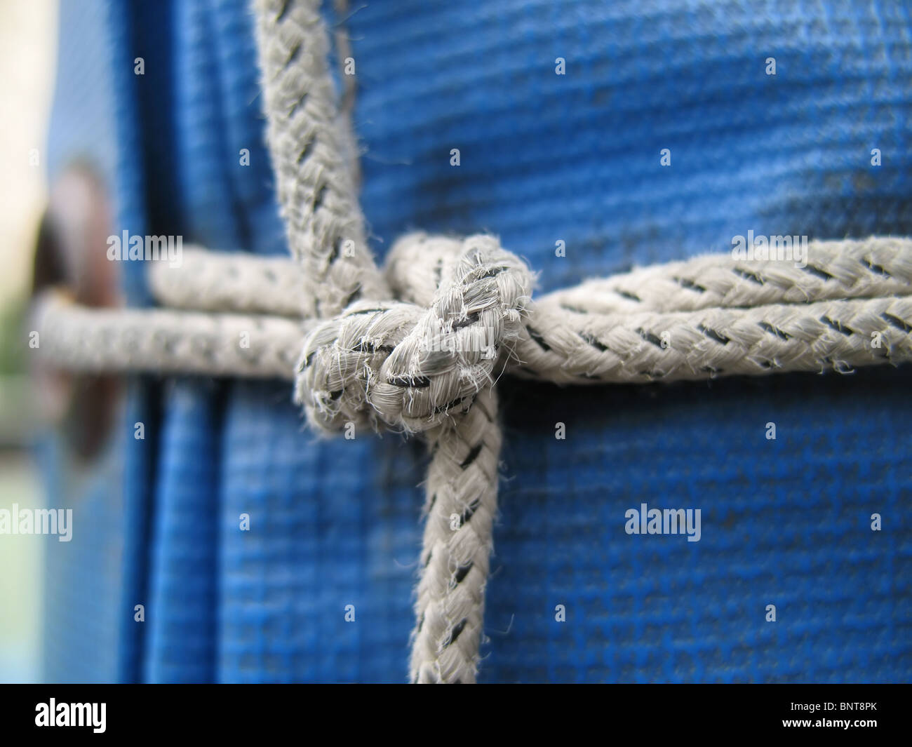 A closeup of a knot made with a strong rope on a blue tarp Stock Photo -  Alamy