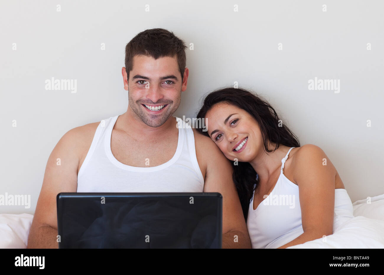 Happy couple using a laptop on the bed Stock Photo - Alamy