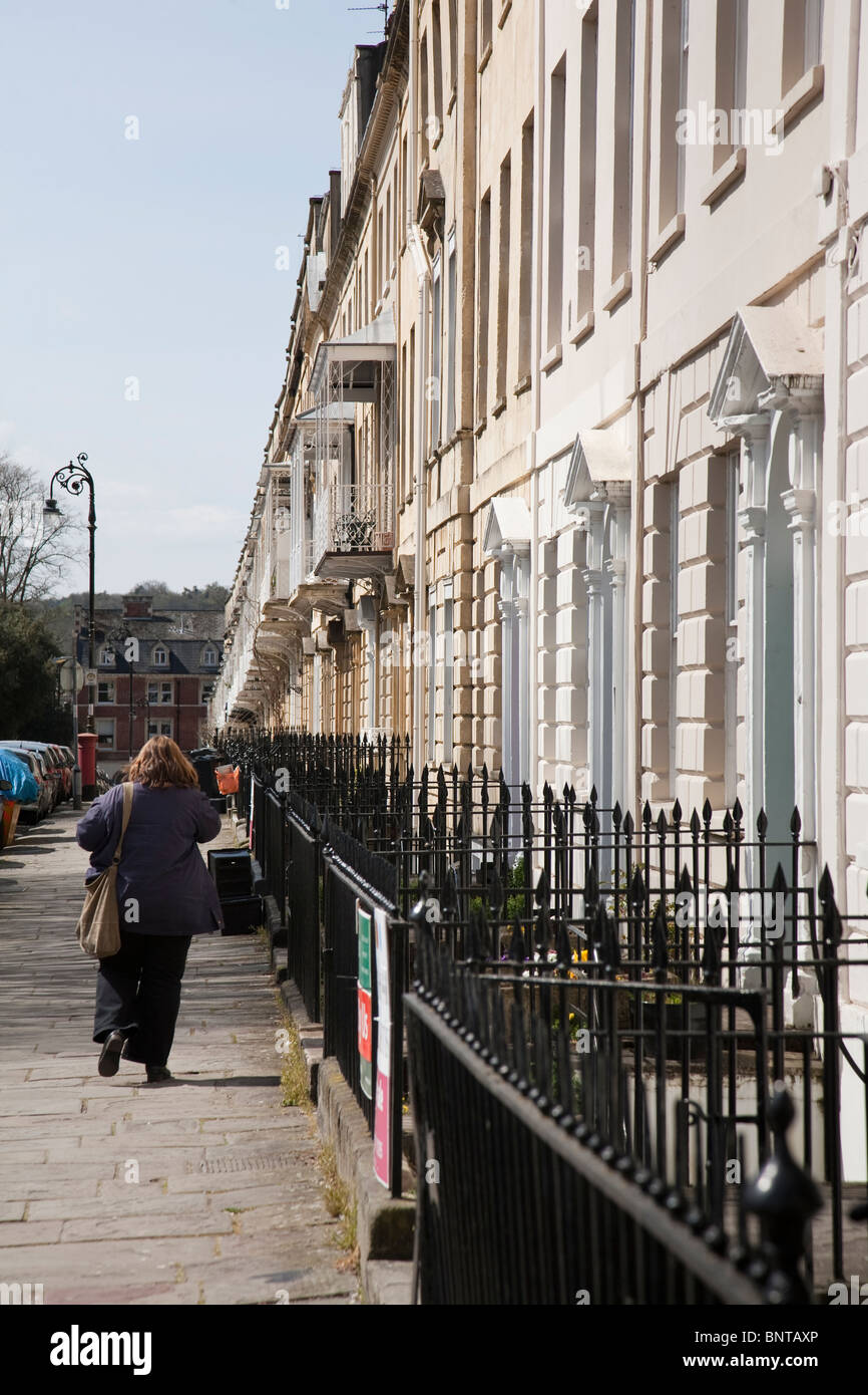 A woman walks past a terrace of Georgian houses on West Mall, Clifton, Bristol, England. Stock Photo