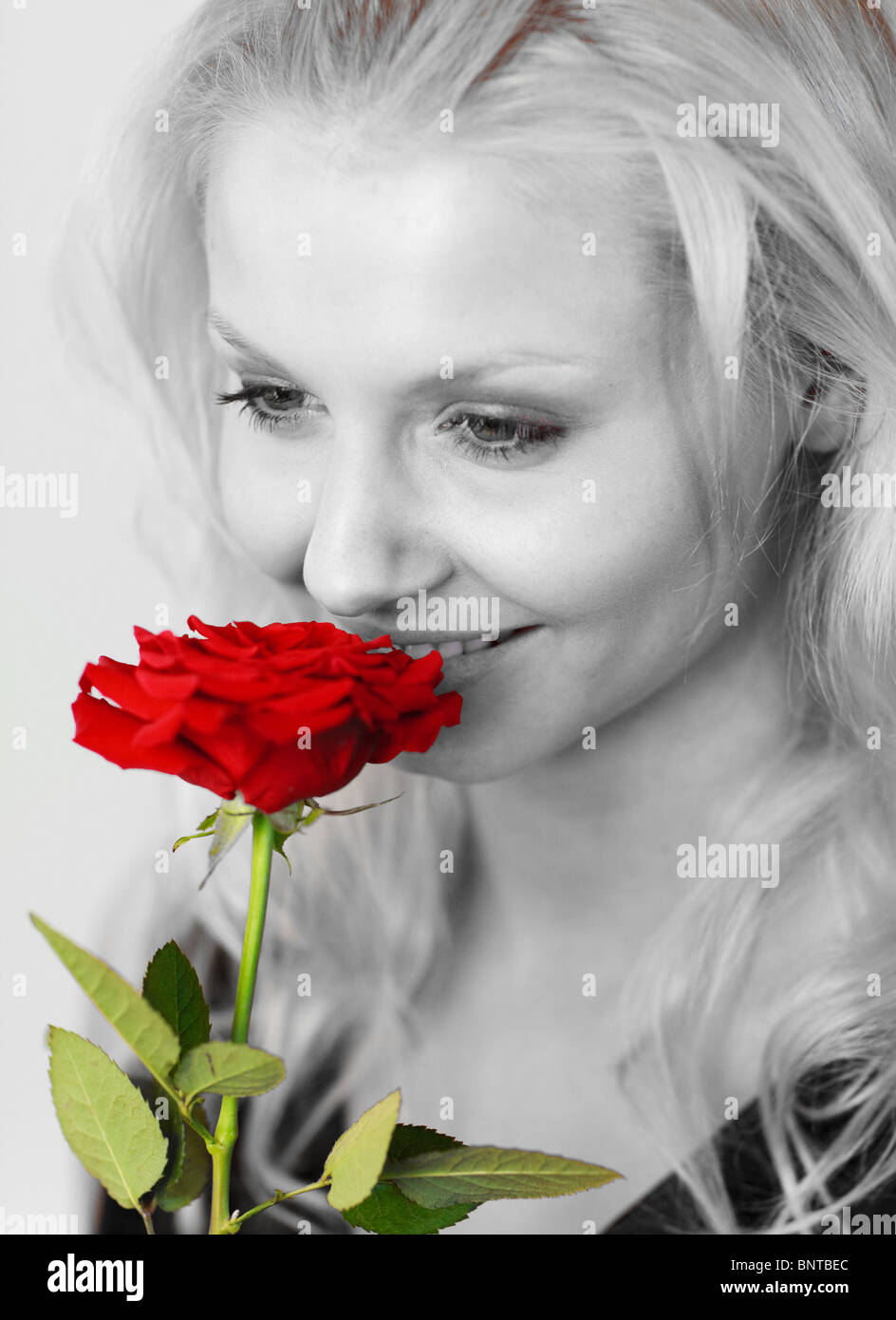 Smiling woman in black and white smelling a red rose Stock Photo - Alamy