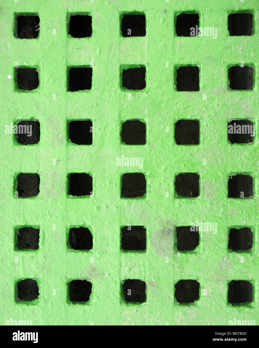 A green drainage cover made from steel with square holes Stock Photo