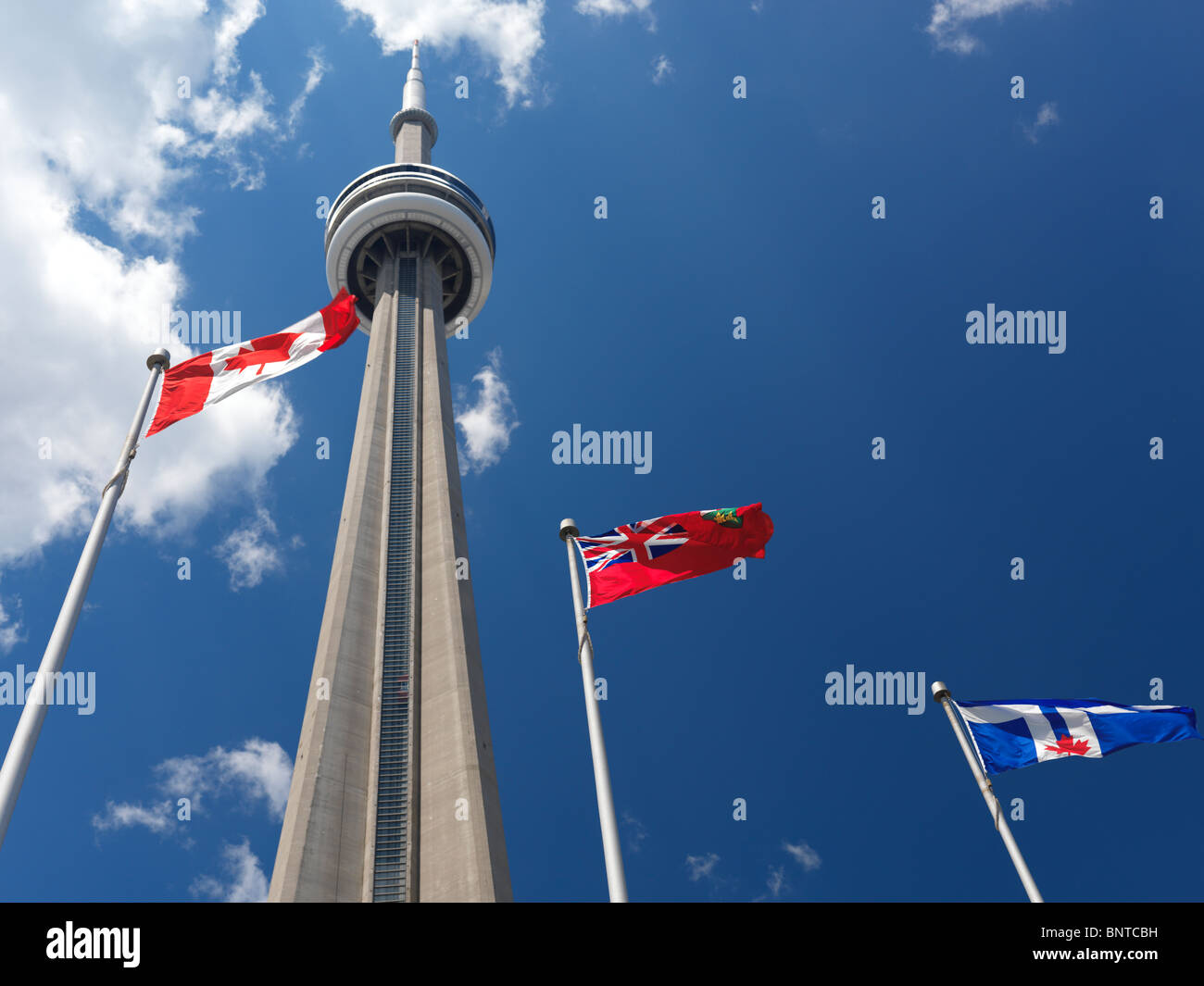 Toronto, Ontario and Canada flags flying in front of CN tower over blue sky Stock Photo