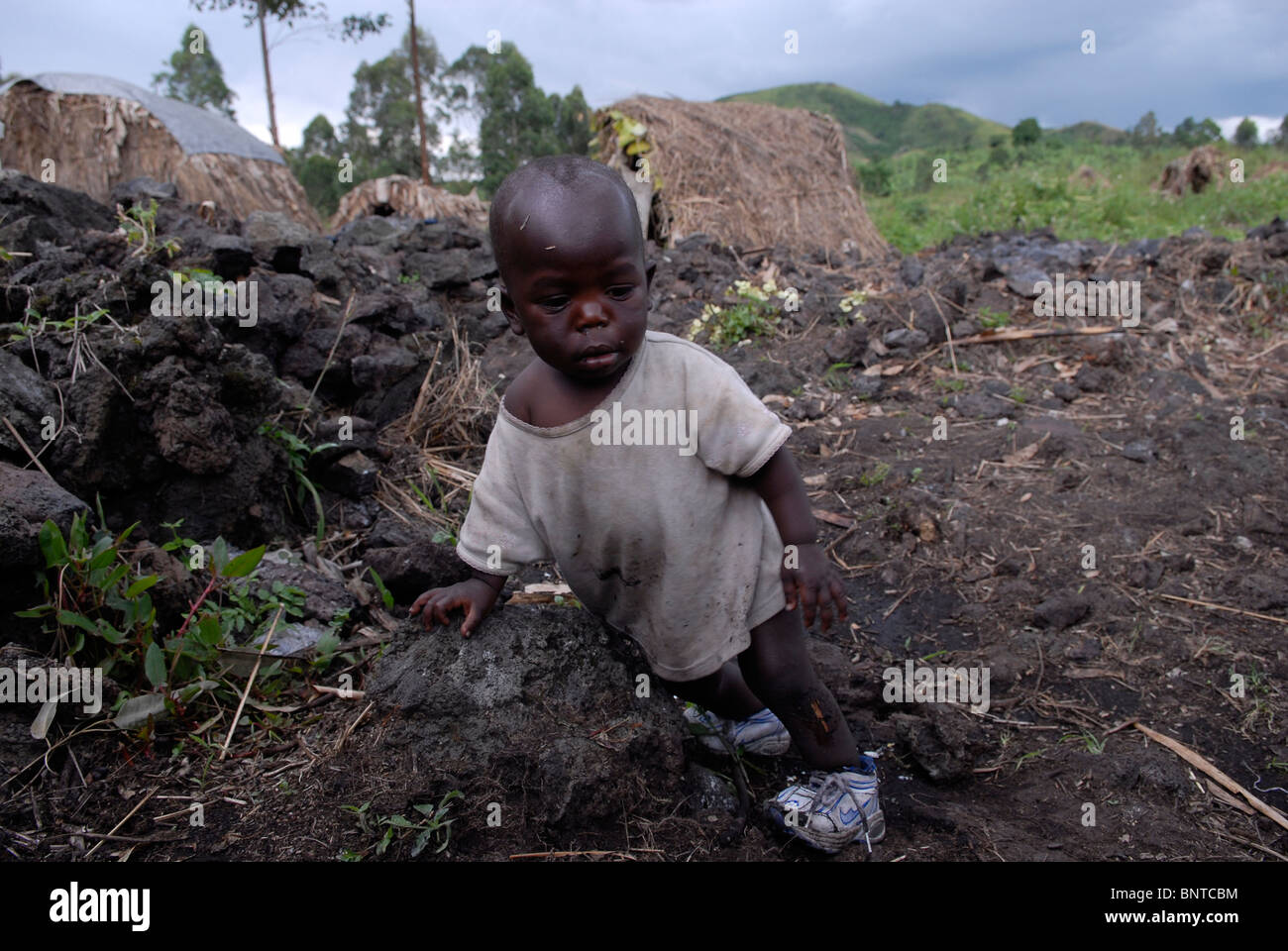 Young Displaced Congolese child amid makeshift straw huts in an IDP camp in North Kivu province DR Congo Africa Stock Photo