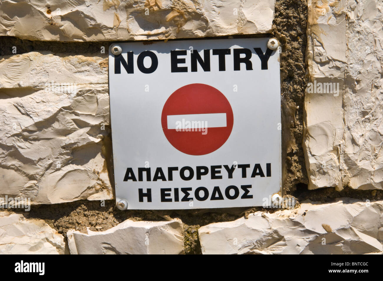 NO ENTRY bilingual Greek English language sign on house wall in Kassiopi Corfu Greece GR Stock Photo