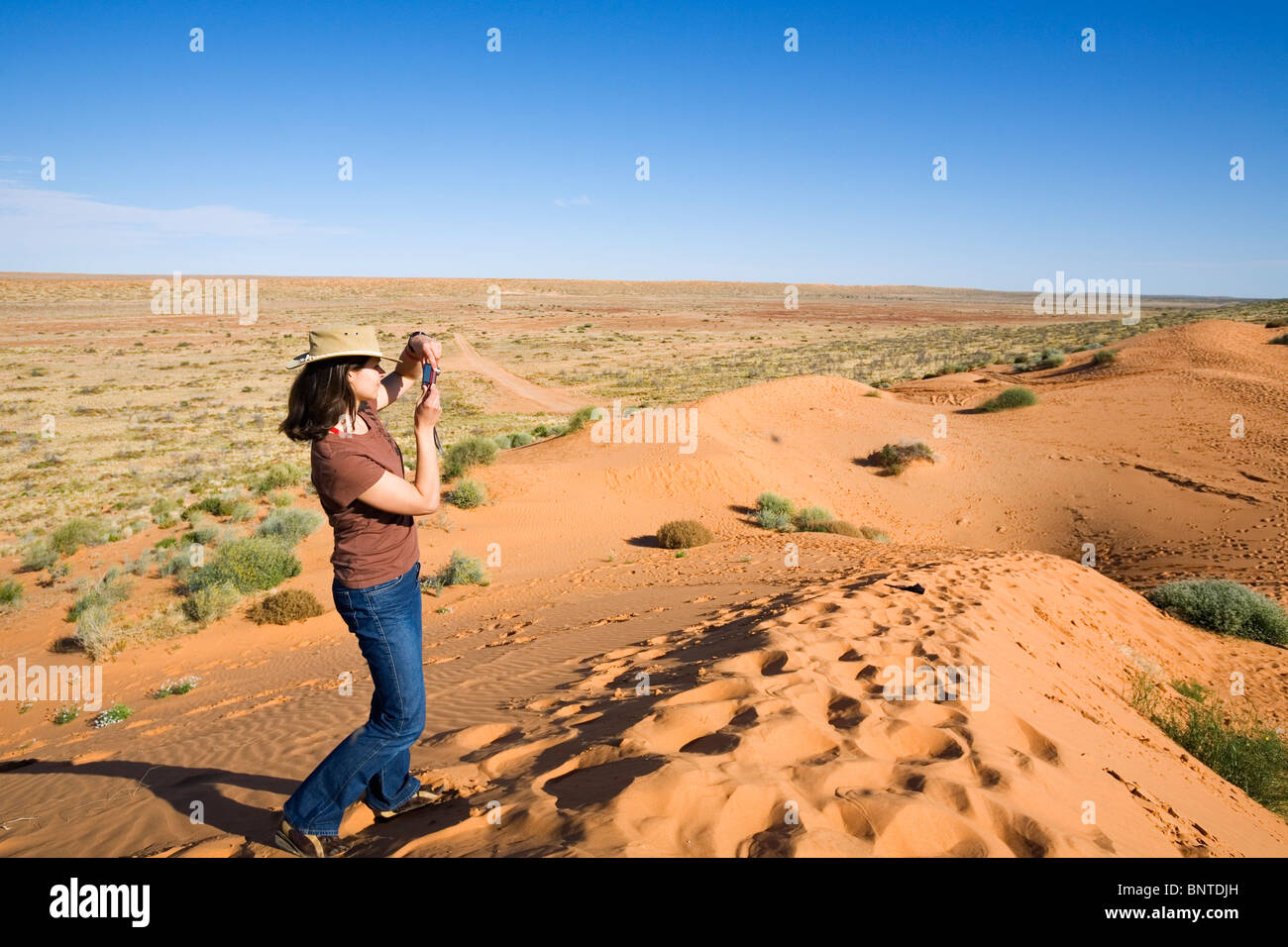 A woman stands a sand dune in the Simpson Desert National Park, Birdsville, Queensland, AUSTRALIA. Stock Photo
