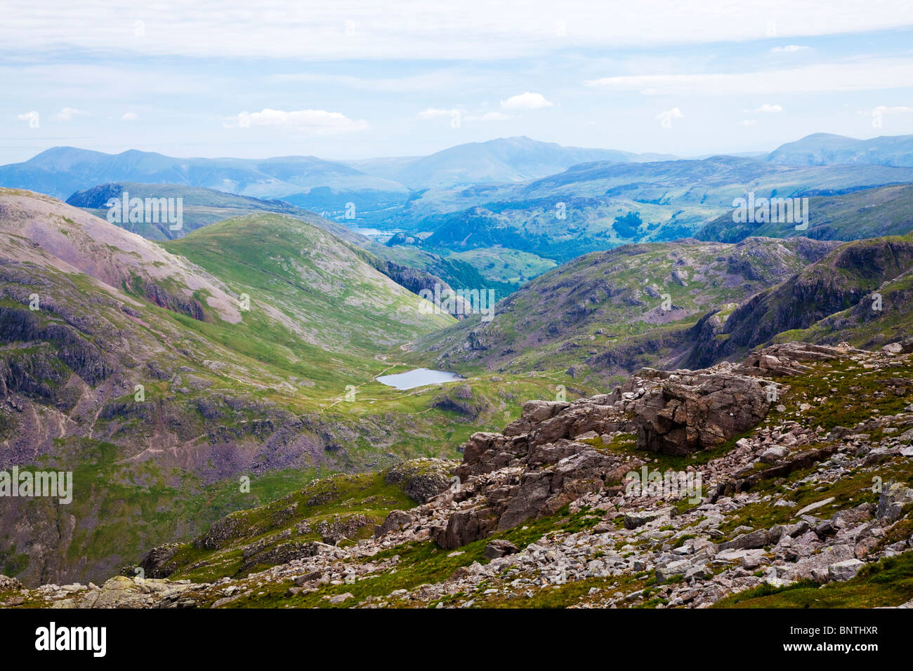 View from summit top of Scafell Pike, towards Styhead Tarn with Derwent Water in far distance. Stock Photo